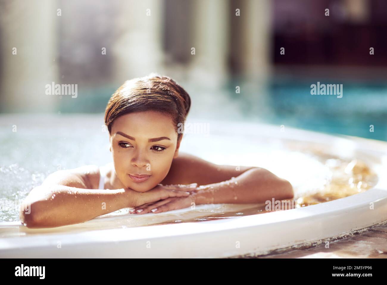 Taking advantage of the soothing benefits of steam. an attractive young woman relaxing in an indoor jacuzzi at a beauty spa. Stock Photo