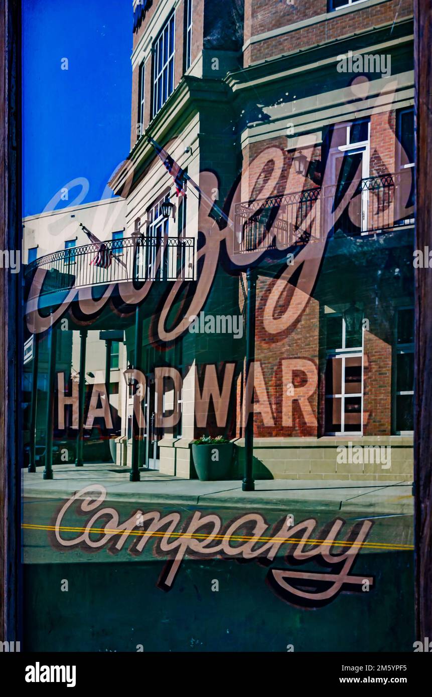 Historic buildings are reflected in the window of Ellzey’s Hardware