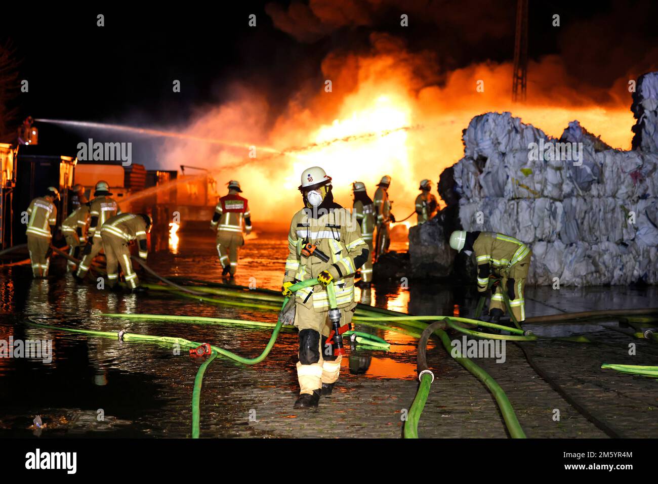 Duesseldorf, Germany. 01st Jan, 2023. Firefighters extinguish a fire in a  warehouse. Bales of paper went up in flames in a major fire at a Düsseldorf  building materials store early on Sunday