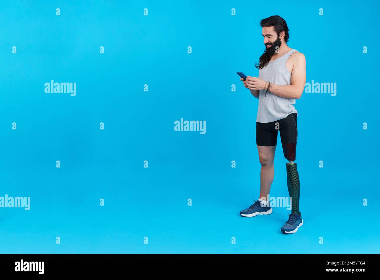 Sportive man with a leg prosthesis using a mobile Stock Photo