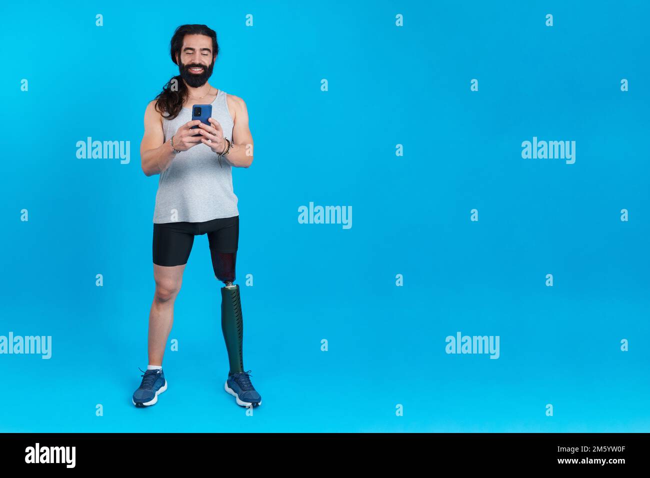 Man with a prosthetic amputated leg using a mobile phone Stock Photo