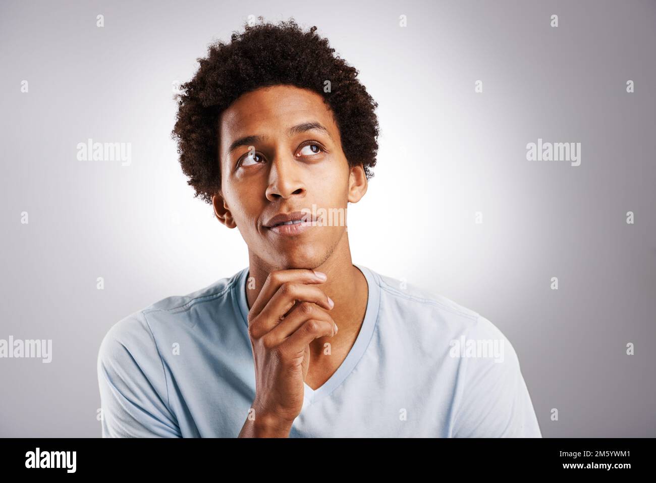 I think its the perfect copyspace...a young man looking thoughtful against a gray background. Stock Photo