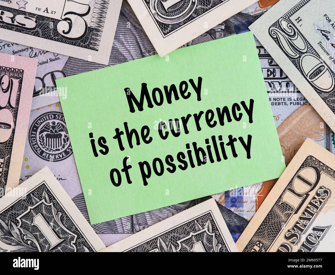 A Green paper note with phrase Money is the currency of possibility on a United States Dollar bills background. Stock Photo