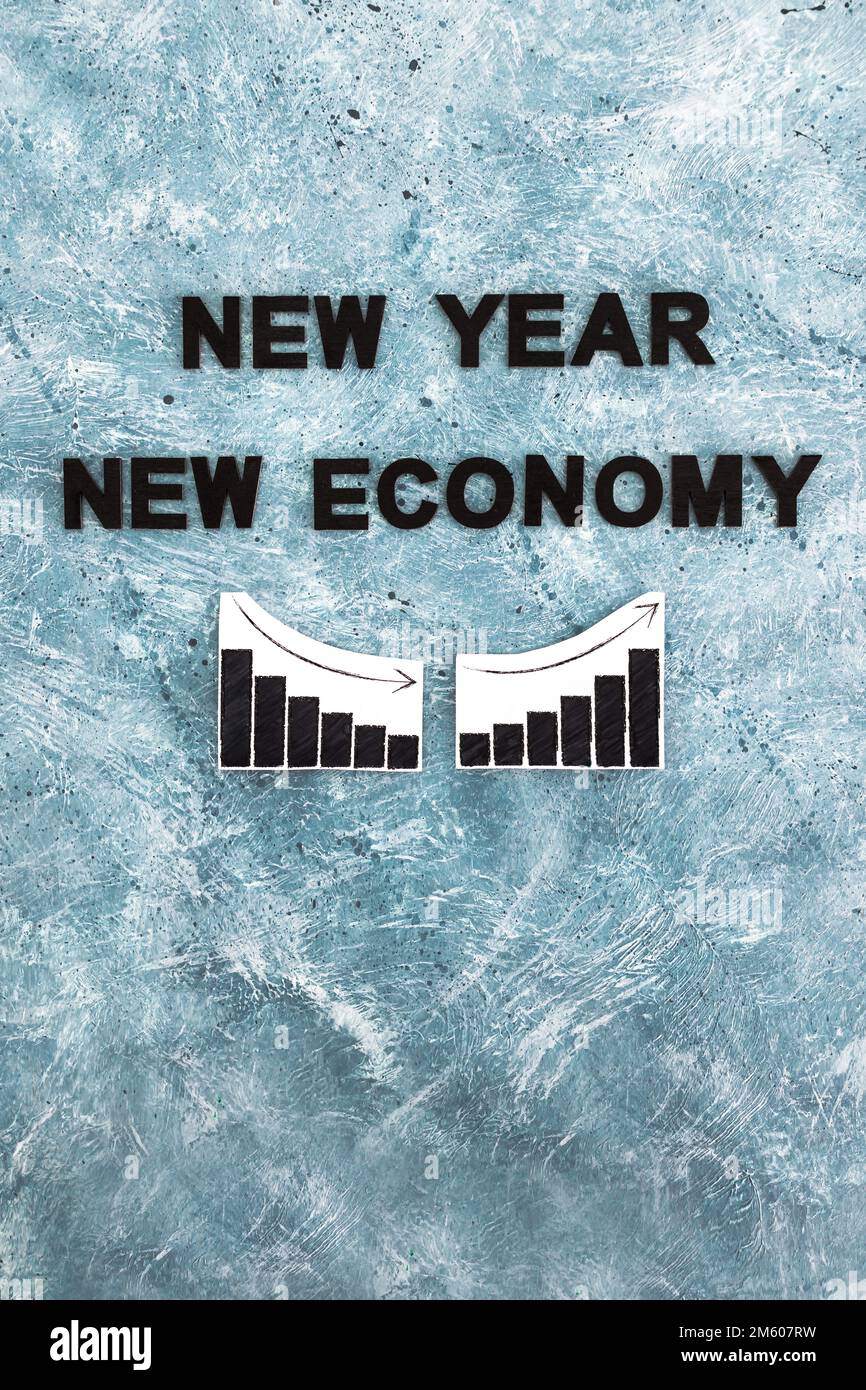 new year new economy text with graphs showing growth stats going down then up again on grey blue background Stock Photo