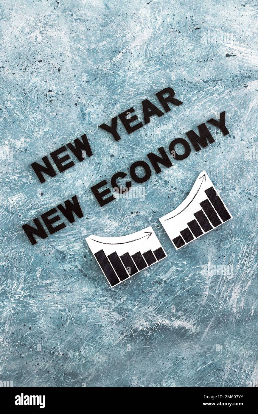 new year new economy text with graphs showing growth stats going down then up again on grey blue background Stock Photo