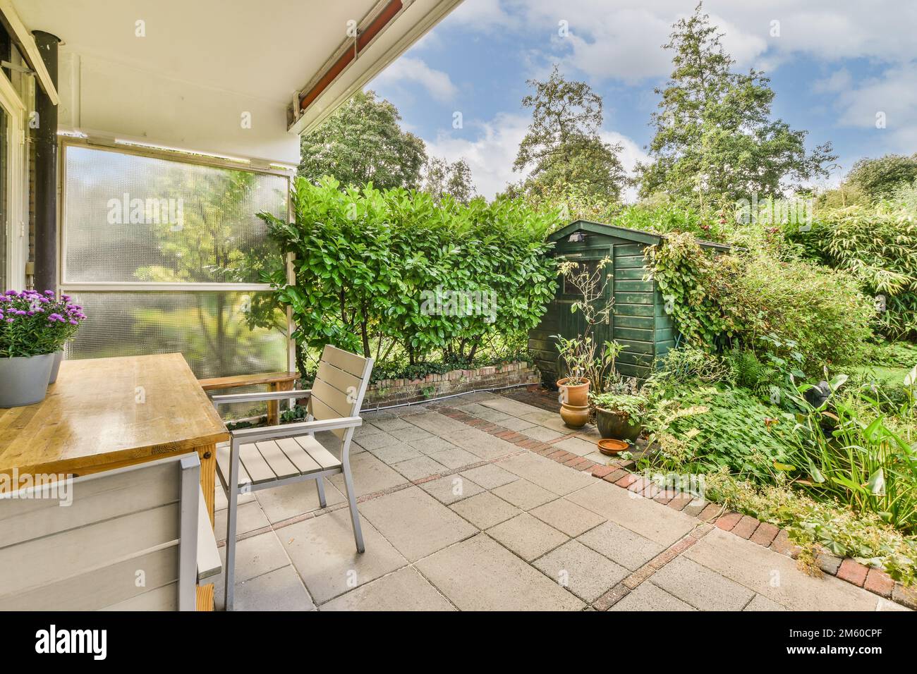 an outside area with some plants and pots on the table in front of the house, looking out to the garden Stock Photo