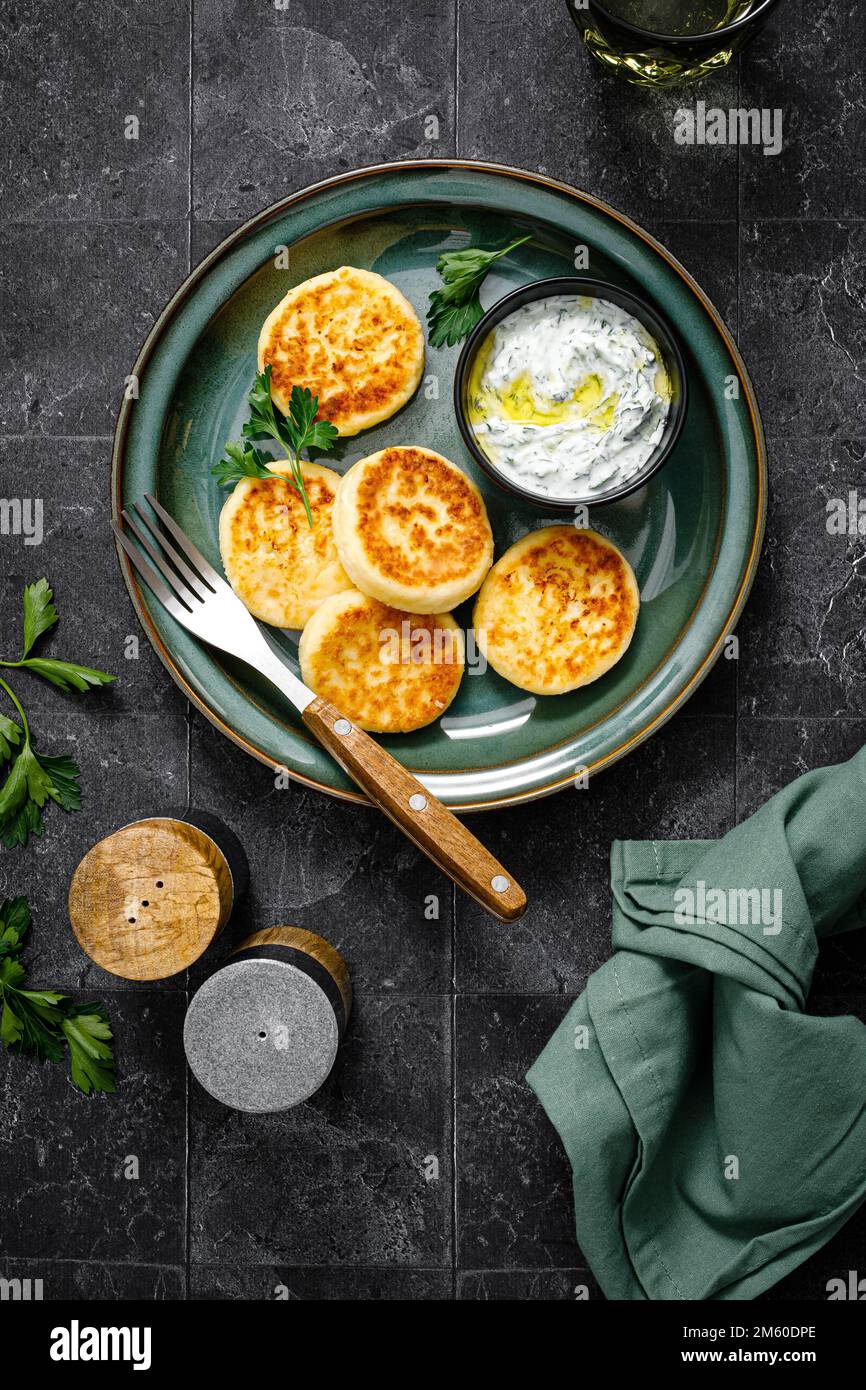 Cottage cheese fritters with greek yogurt tzatziki sauce, top view Stock Photo
