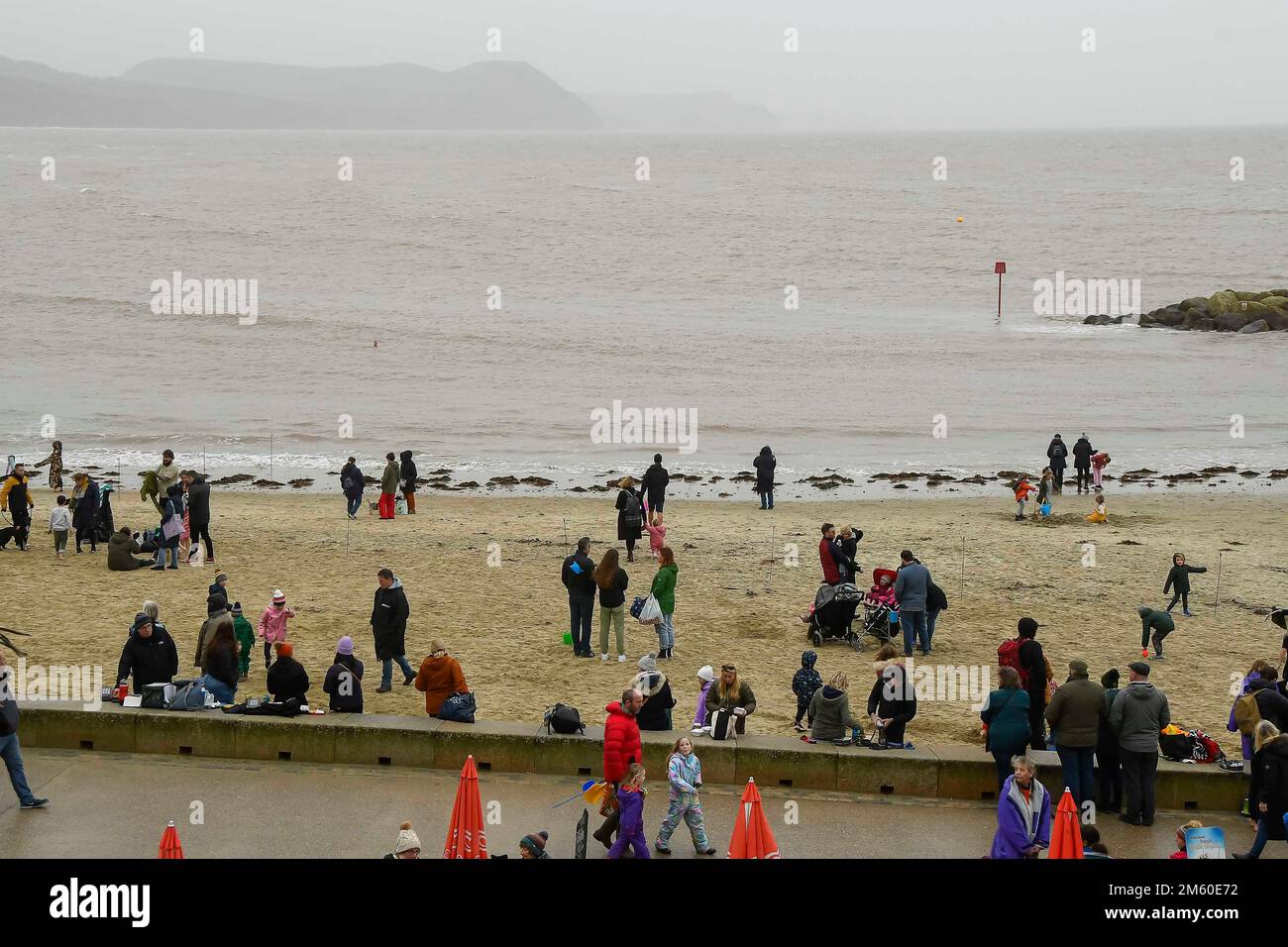 Lyme Regis, Dorset, UK.  1st January 2023.  UK Weather.  Families and visitors on the beach at Lyme Regis in Dorset on a damp and overcast New Years Day.  Picture Credit: Graham Hunt/Alamy Live News Stock Photo