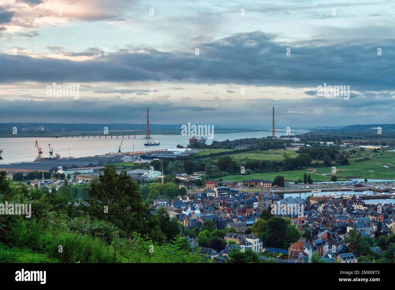 Panoramic view of the houses of the old town and the Seine with the Pont de Normandie cable-stayed bridge from Mont-Joli hill, dusk, Honfleur Stock Photo