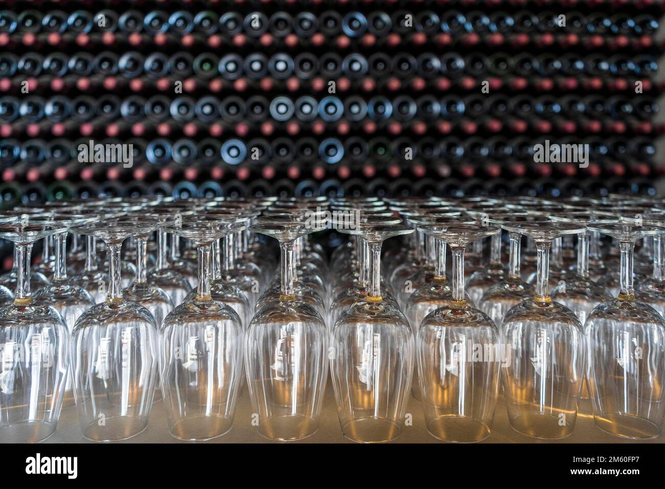 Empty wine glasses with many stacked bottles as a background, preparation to wine tasting in the winery of Lanzarote, Spain Stock Photo