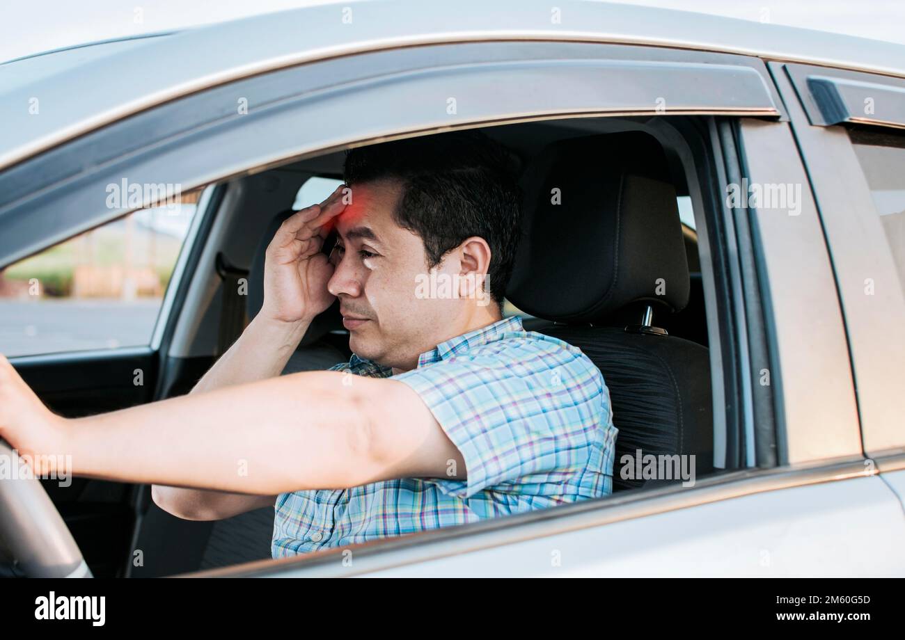 A driver with a headache in traffic, fatigued driver stuck in traffic, concept of a fatigued man in his car, stressed out. A suffering person with a Stock Photo