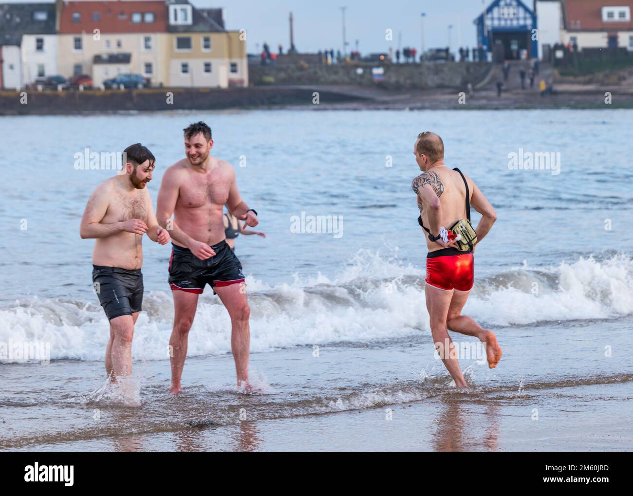 North Berwick, East Lothian, Scotland, UK, 1st January 2023, Loony Dook: The annual dip in the Firth of Forth returns after a gap due to the pandemic in West Bay in the seaside town. A man wearing a Christmas pair of swimming trunks running into the sea. Credit Sally Anderson/Alamy Live News Stock Photo