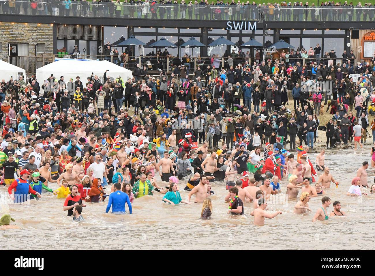 Lyme Regis, Dorset, UK.  1st January 2023.  Hundreds of New Years Day revellers in fancy dress, watched by huge crowds, take part in the annual Lyme Lunge charity swim at Lyme Regis in Dorset in aid of Mencap and the National Heart Foundation on an overcast damp day.  Picture Credit: Graham Hunt/Alamy Live News Stock Photo