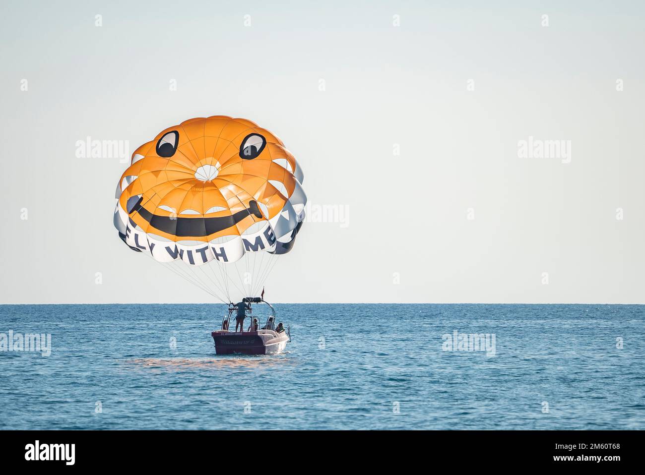 People in boat with open parachute preparing for parasailing on