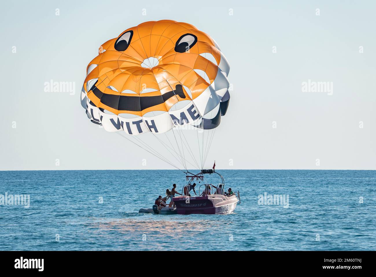 People in boat with open parachute preparing for gliding on seascape