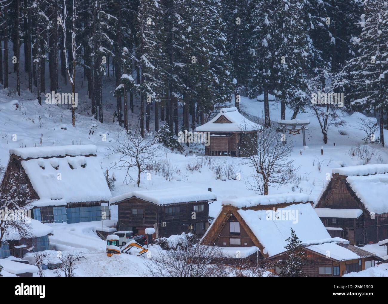 Steep roofs covered with snow in mountain village by woods Stock Photo