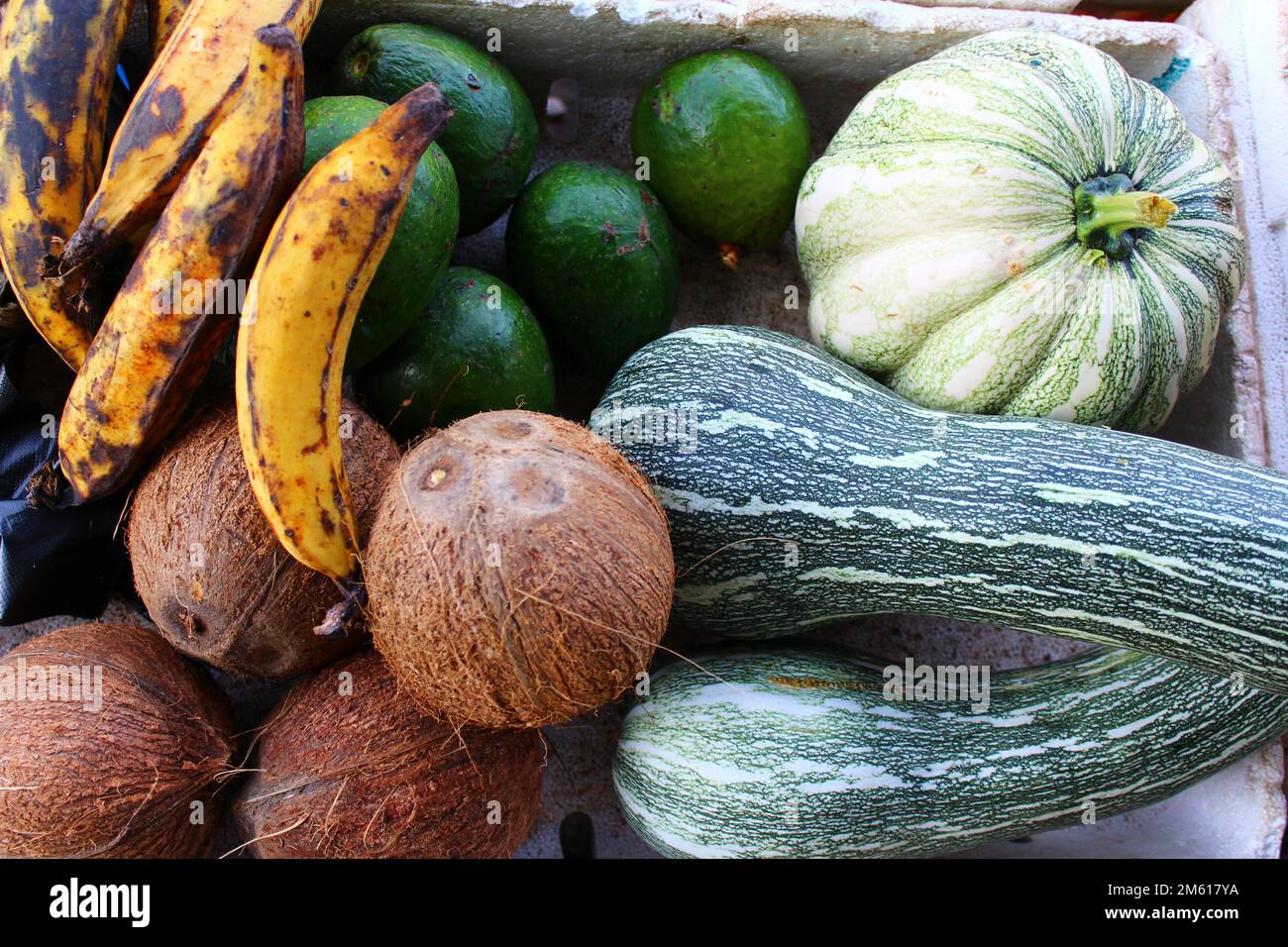 coconut, butter pear avocado and banana plantain on a market stall Stock Photo