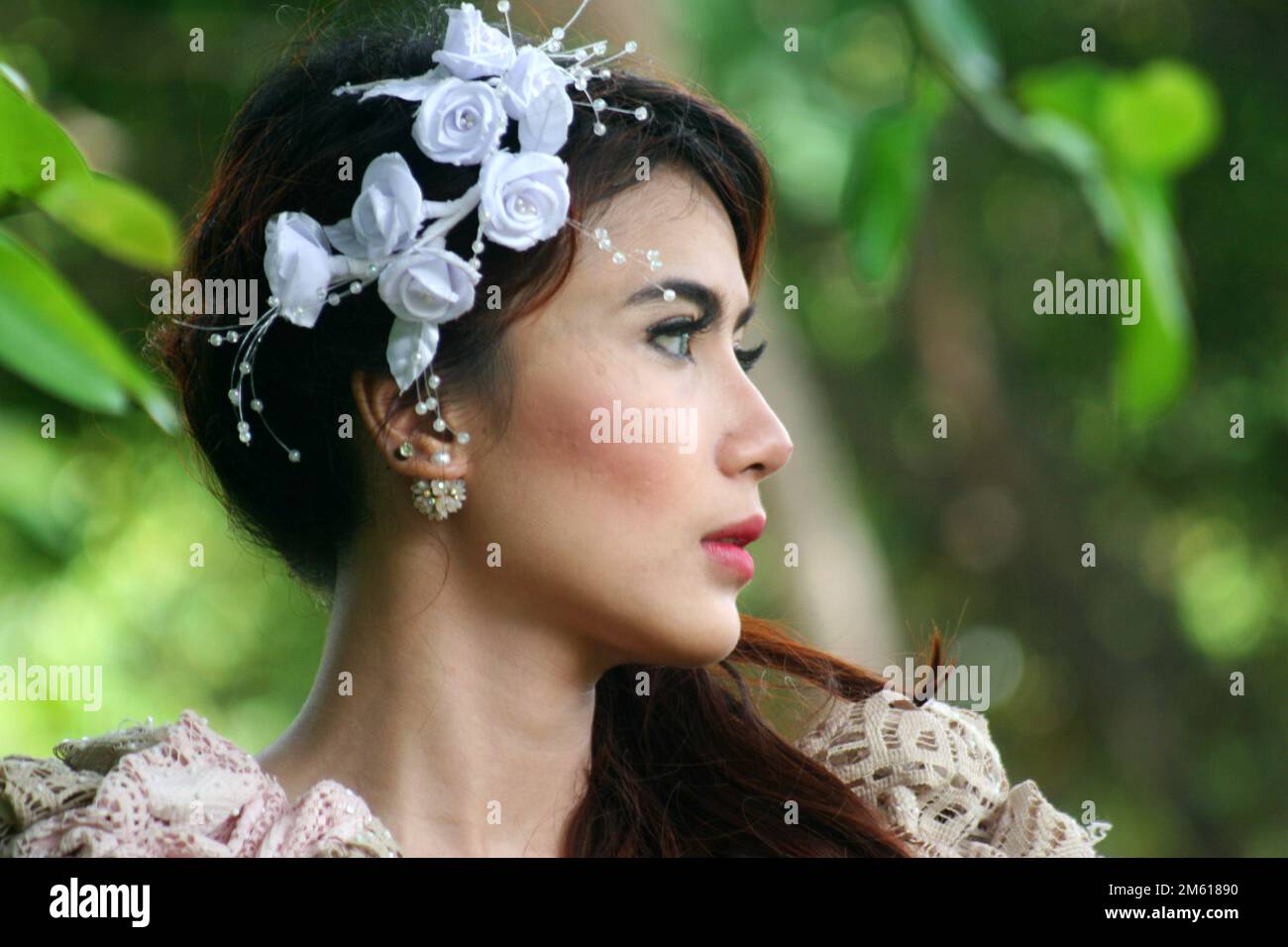 portrait of an Indonesian woman wearing a white flower decoration in her hair. she was turning his head to the side Stock Photo