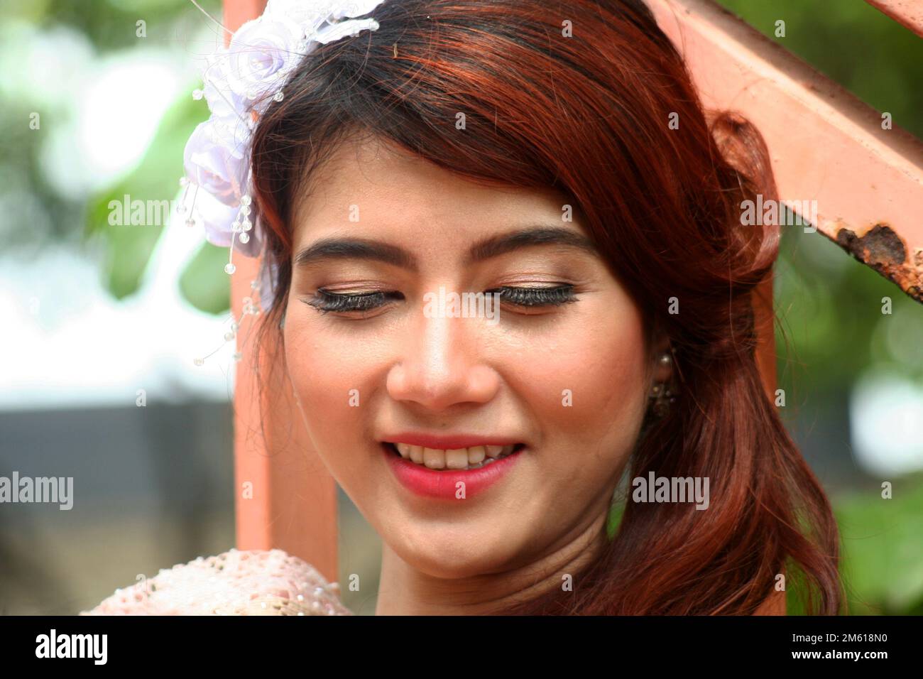 portrait of a smiling Indonesian woman. she wears white flower ornaments in her hair Stock Photo