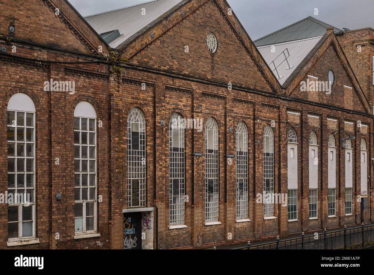 Detail of some old industrial buildings with tall arched windows. Engineering, business premises, workshop, industry concept. Stock Photo
