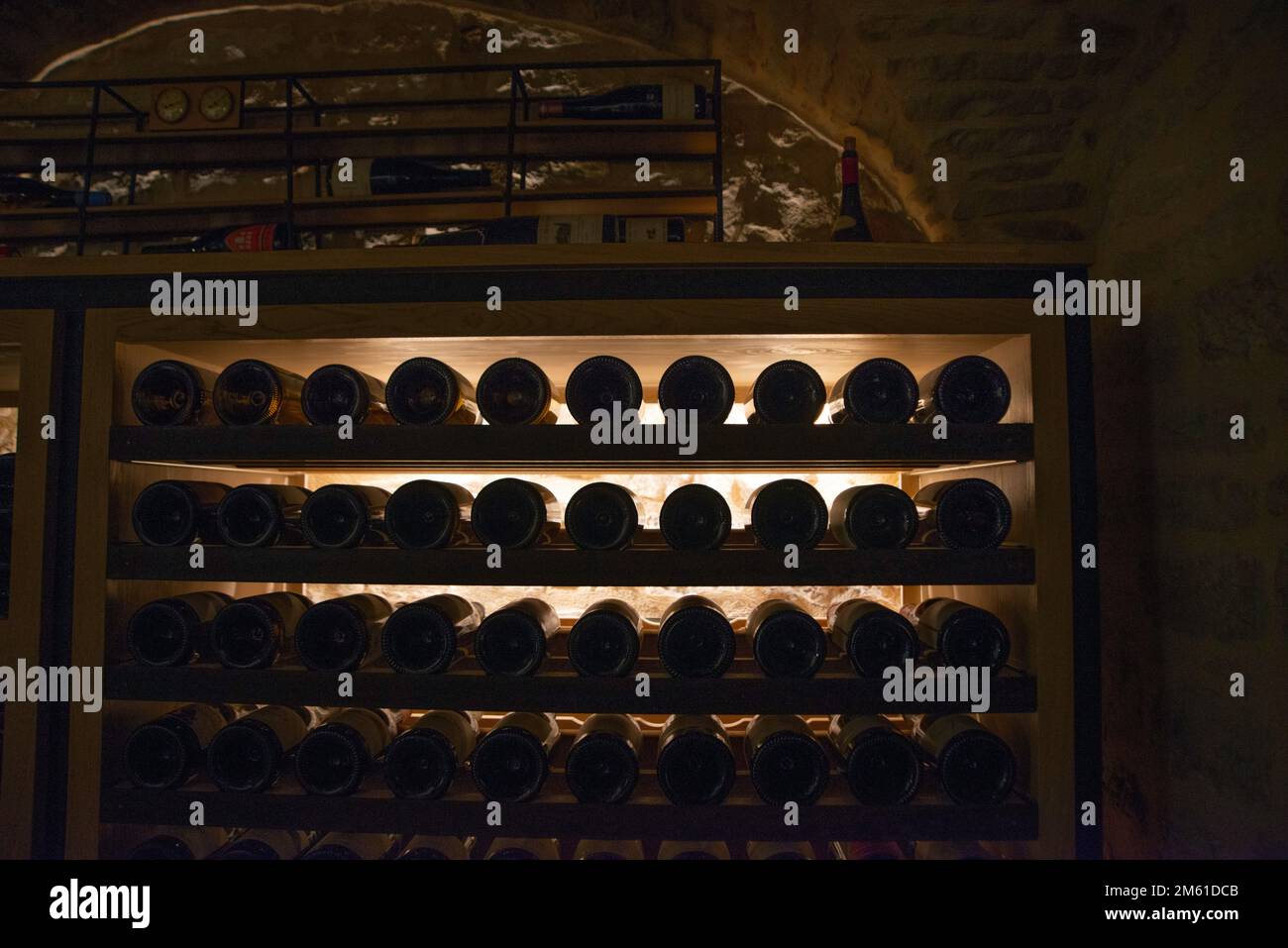 Backlit wine bottles in an underground wine cave Stock Photo