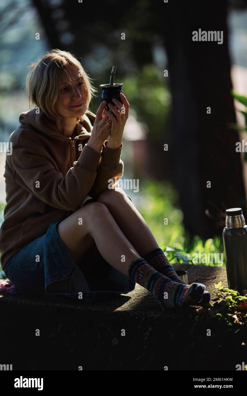 A woman sitting in the park with a cup of Mate. Stock Photo
