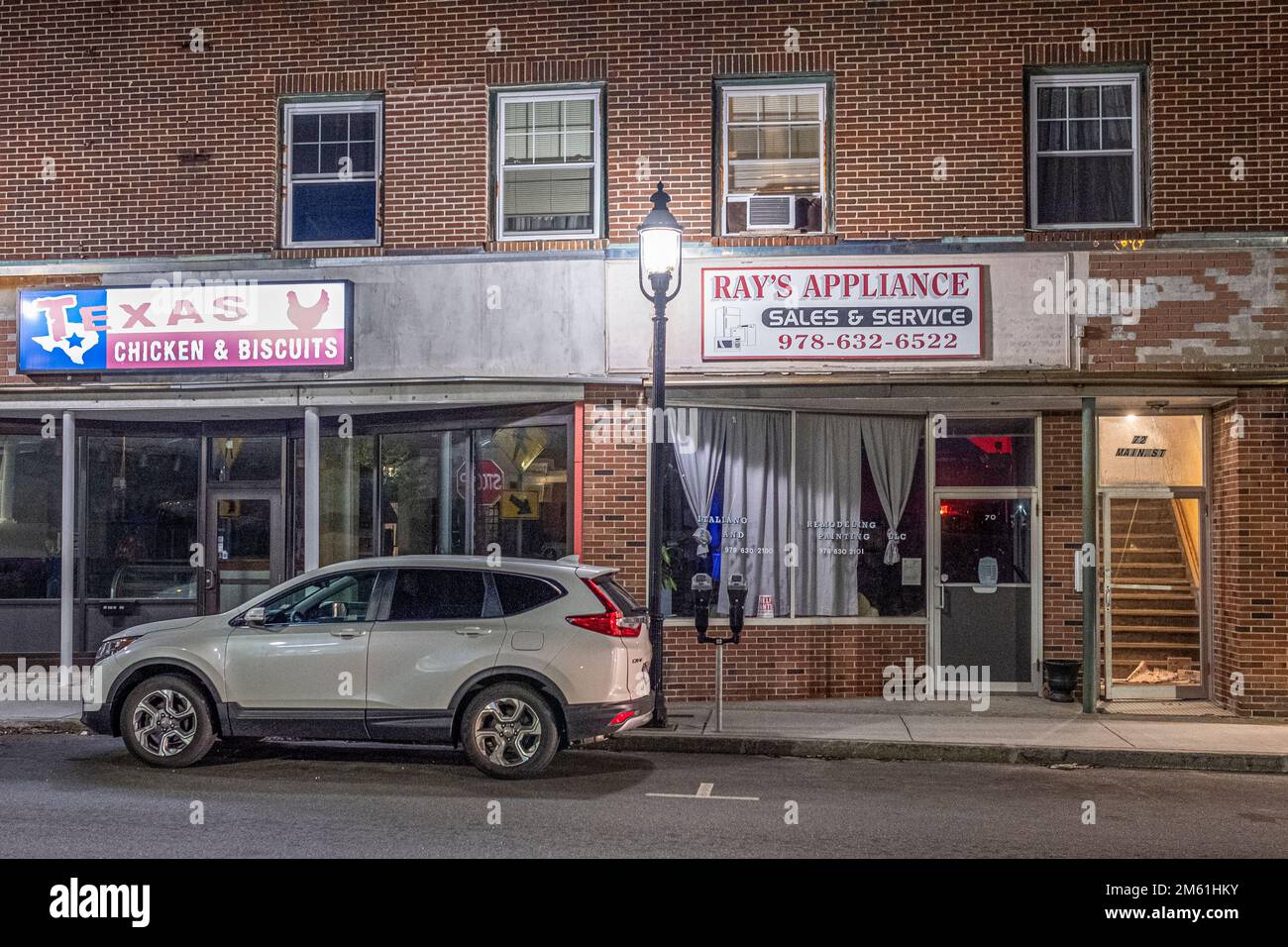 A car parked on the street next to a couple of stores in Gardner