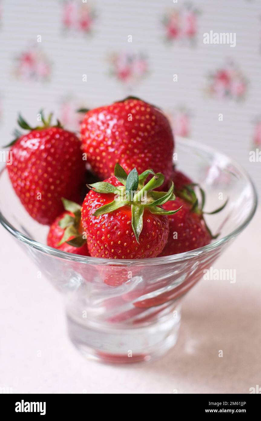 Fresh strawberries lie in a glass bowl on a white background of tea