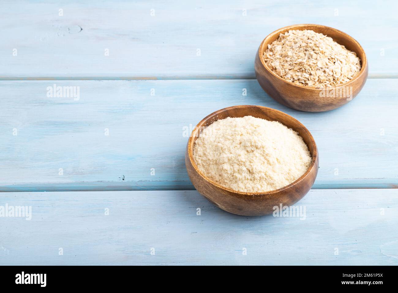 Powdered milk and oatmeal baby food mix, infant formula on blue wooden background. Side view, copy space, artificial feeding concept. Stock Photo