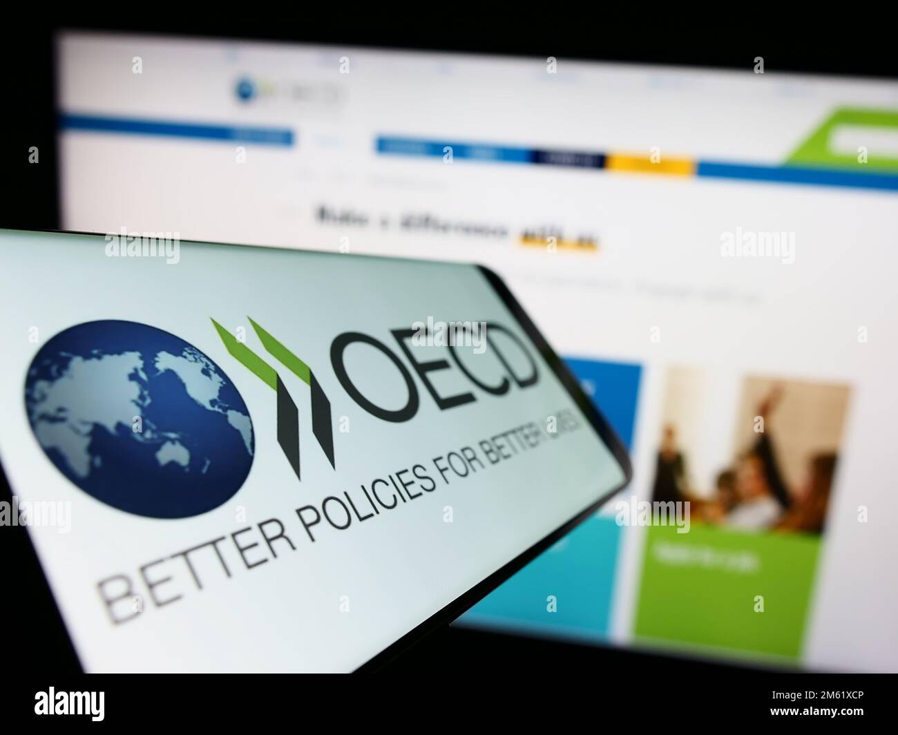 Smartphone with logo of intergovernmental organisation OECD on screen in front of website. Focus on center-left of phone display. Stock Photo