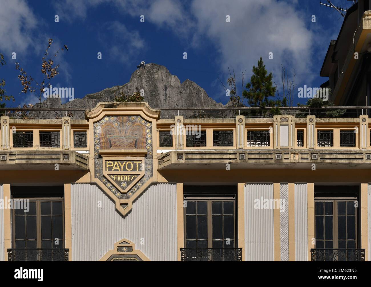 Top of the Art Deco building of the Payot Bank in the centre of Chamonix with the Brevent cable car station on the peak in the background, France Stock Photo