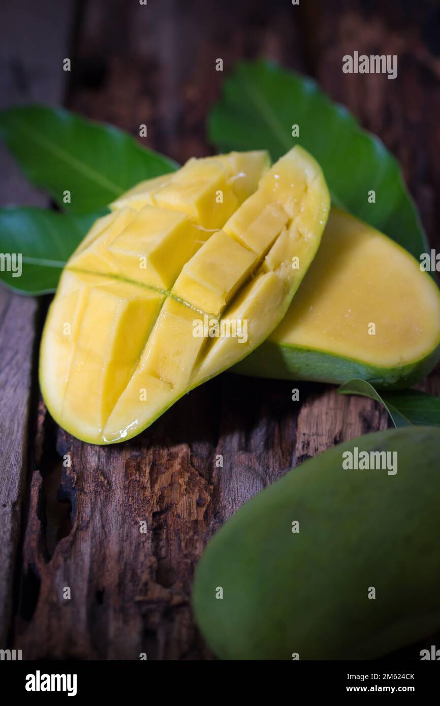 Mango fruit and mango cubes on the wooden table. Stock Photo