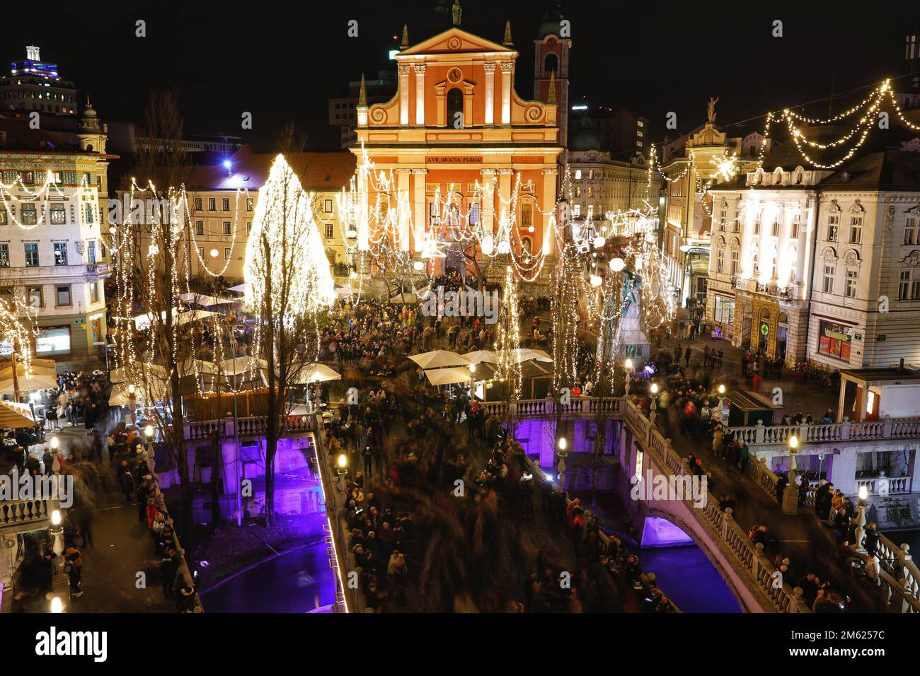 Crowds gather in the brightly lit Presernov Trg Square, by the three bridges, Ljubljana, Slovenia for 2022 / 2023 New Year's Eve celebrations Stock Photo