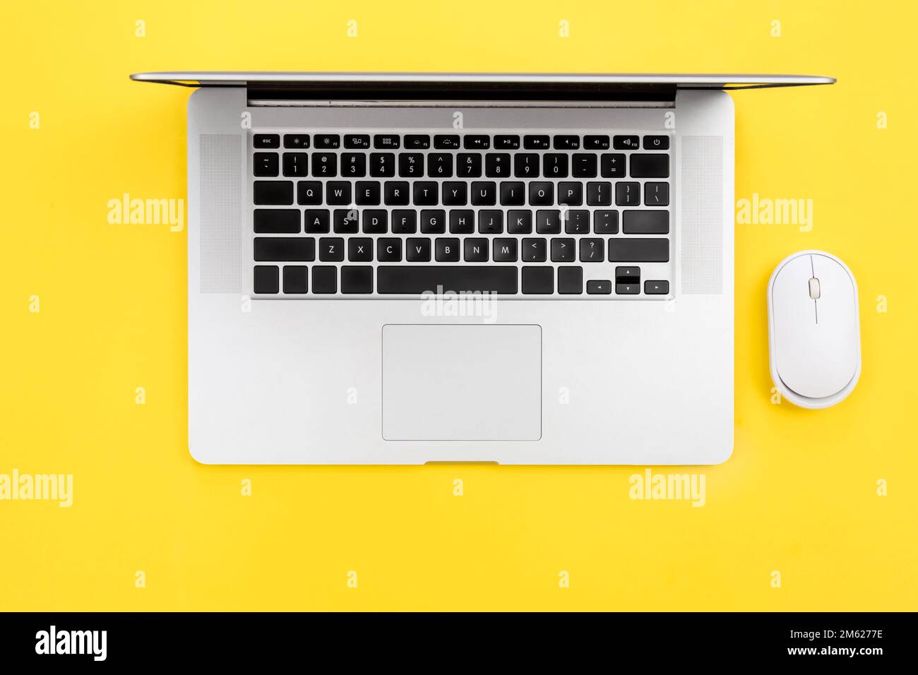 Laptop and computer mouse on yellow background, flat lay. Stock Photo