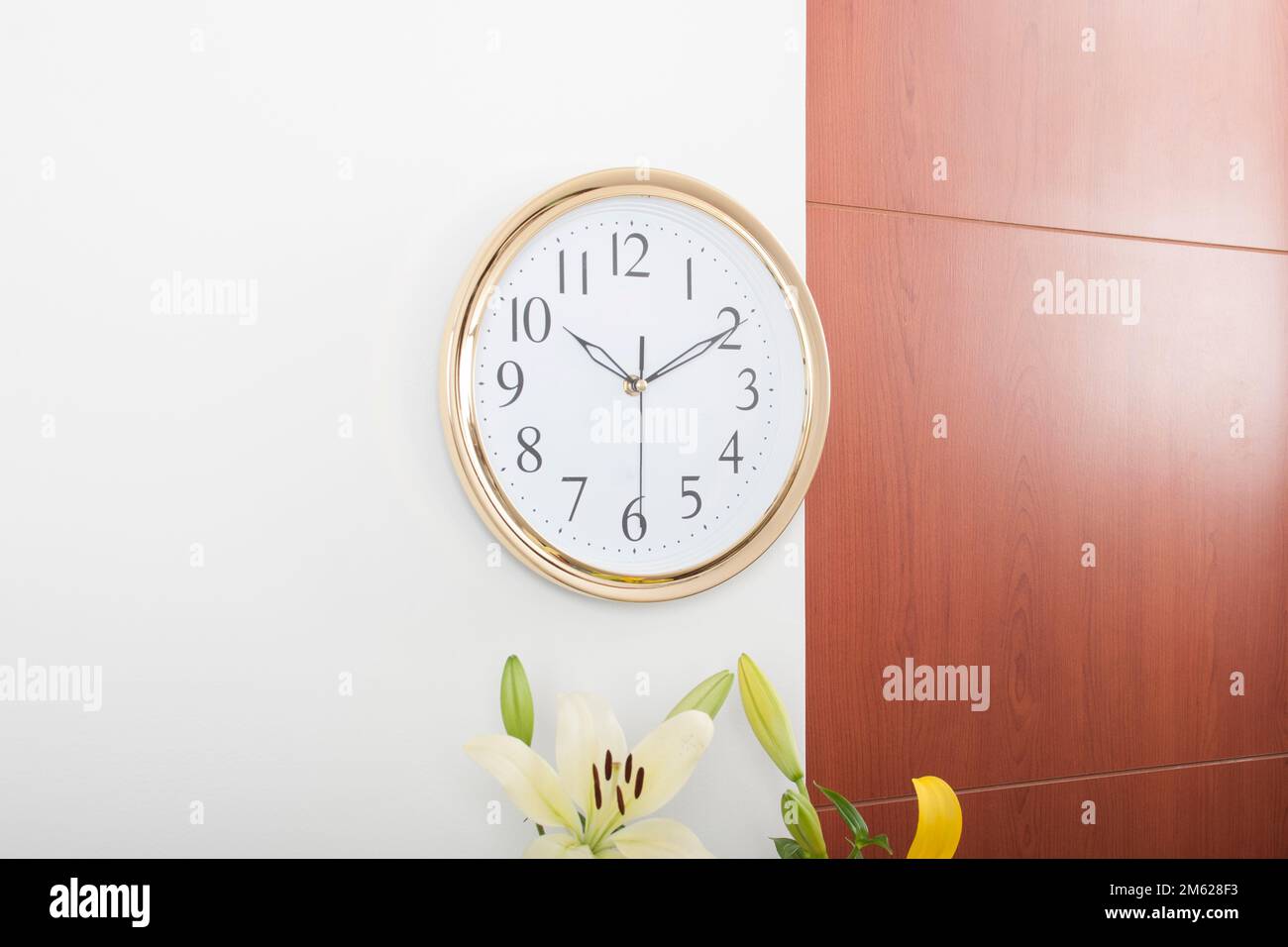 Round wall clock gold trim black numbers on white background Stock