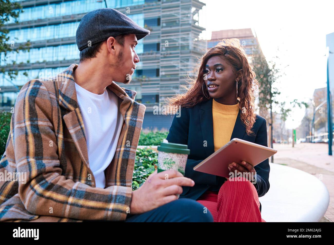 Two colleagues talking about work while sitting outdoors. Stock Photo