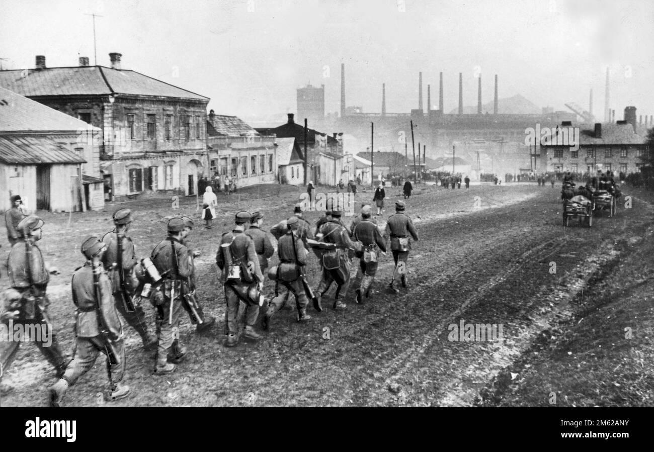 Entry of German troops into Donetsk in Ukraine during Operation Barbarossa, the nazi invasion of the Soviet Union. There is a cartoonish or illustrated look to the soldiers at the rear that may indicate that this is a composite image rather than a straight photo. Only the three lead soldiers look real to me. Stock Photo