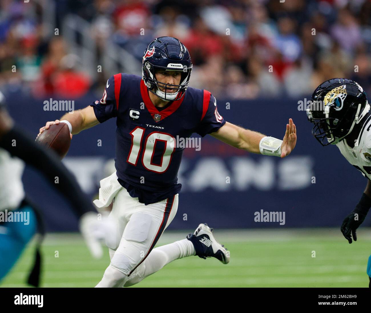 Houston, Texas, USA. January 1, 2023: Texans quarterback Davis Mills (10)  scrambles to escape Jaguars linebacker Devin Lloyd (33) during an NFL game  between the Houston Texans and the Jacksonville Jaguars on