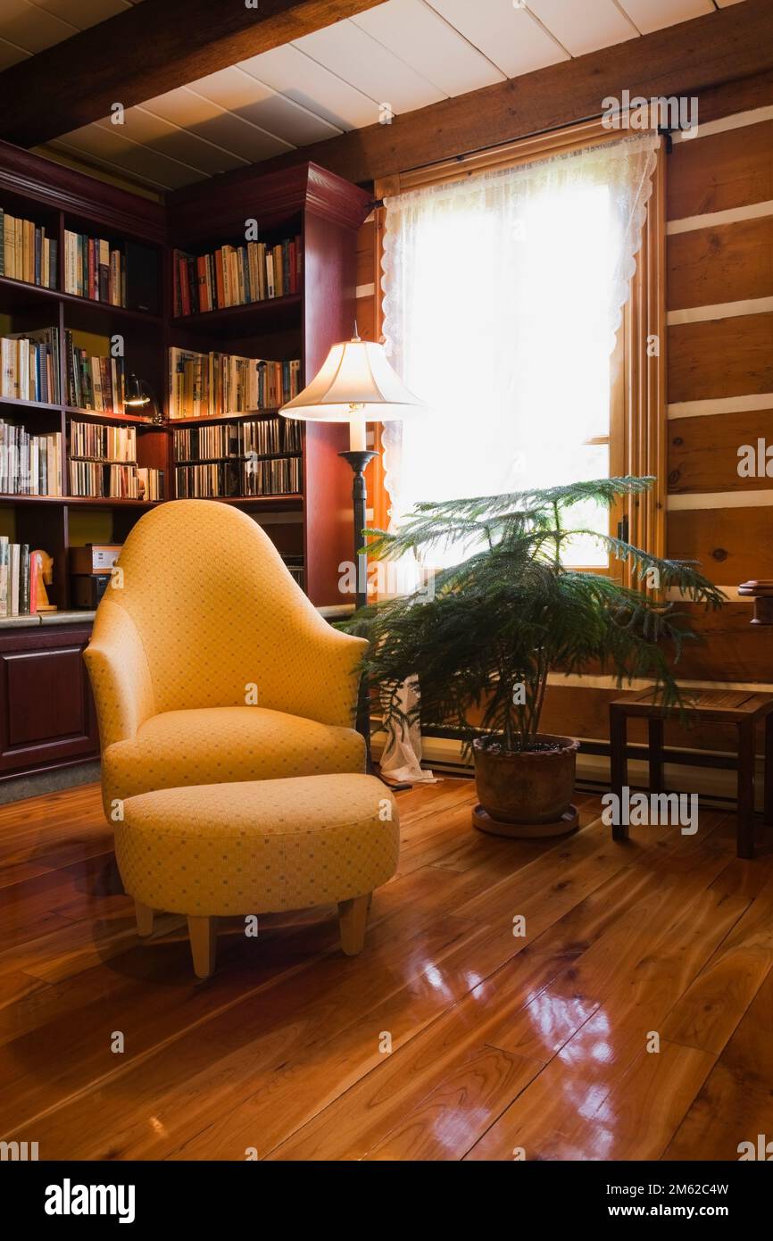 Yellow upholstered armchair and ottoman in living room with varnished