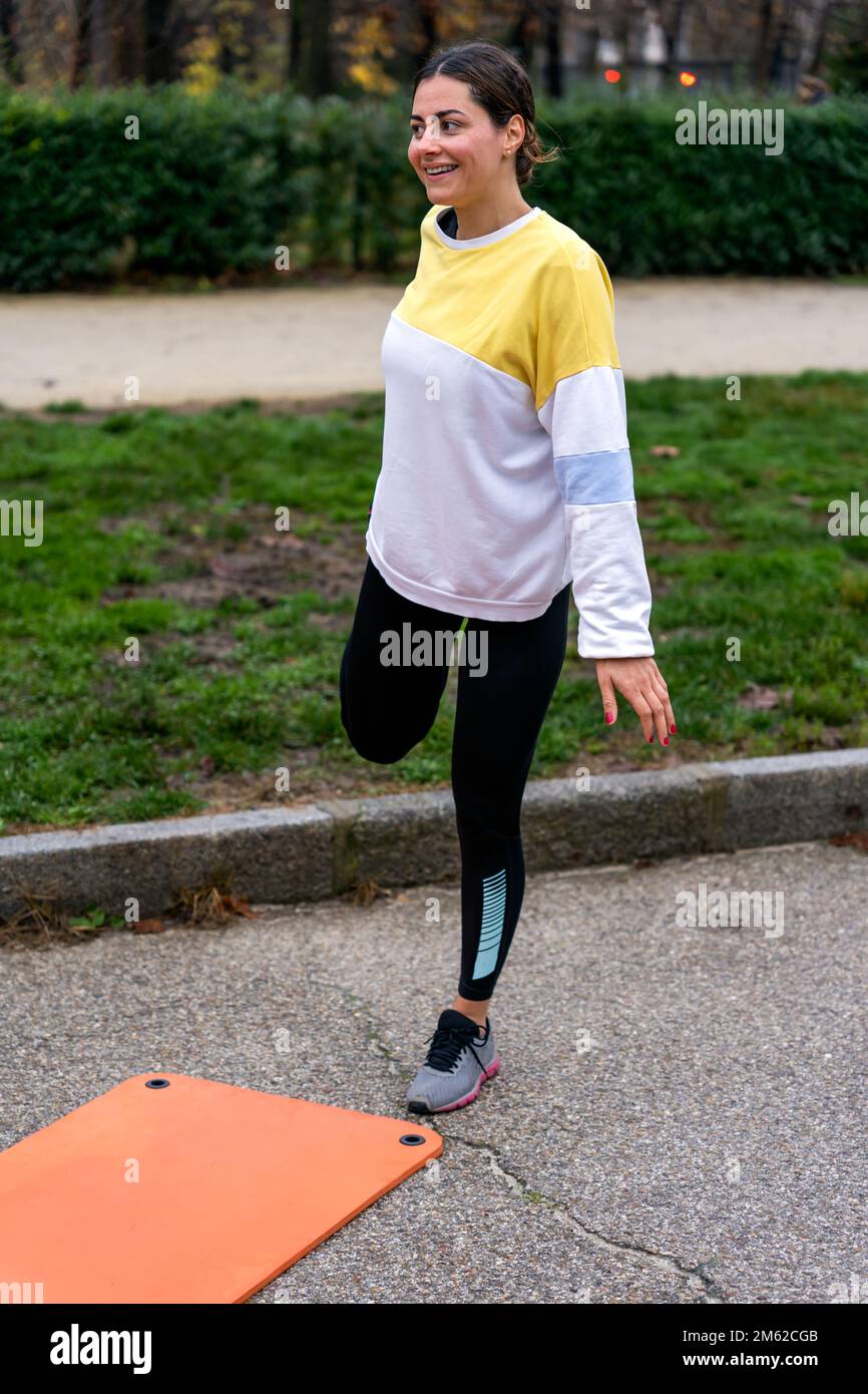 Full body of young female athlete in leggings standing in park near