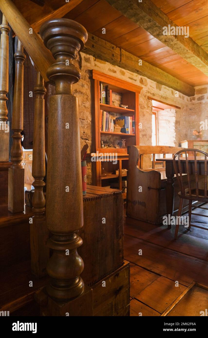 Old wooden staircase with turned newel post and railing in dining room inside old circa 1850 cottage style fieldstone home. Stock Photo