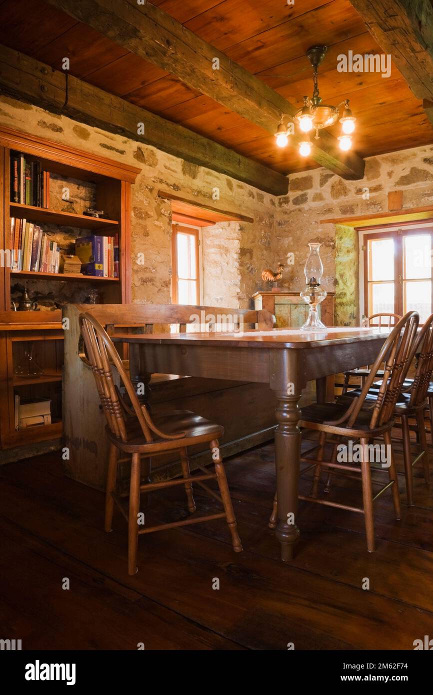 Antique wooden dining table and chairs in dining room inside old circa 1850 cottage style fieldstone home. Stock Photo