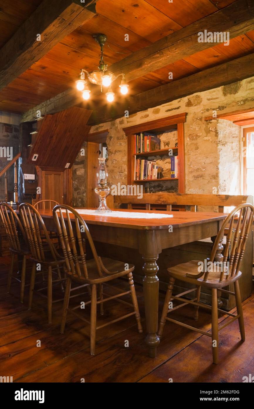 Antique wooden dining table and chairs in dining room inside old circa 1850 cottage style fieldstone home. Stock Photo