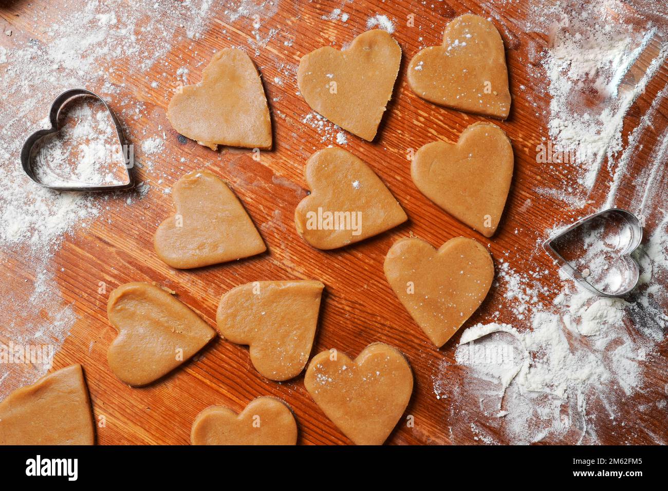 Heart cookies out dough and molds on table with flour. Valentines Day celebration. Home baking. Stock Photo