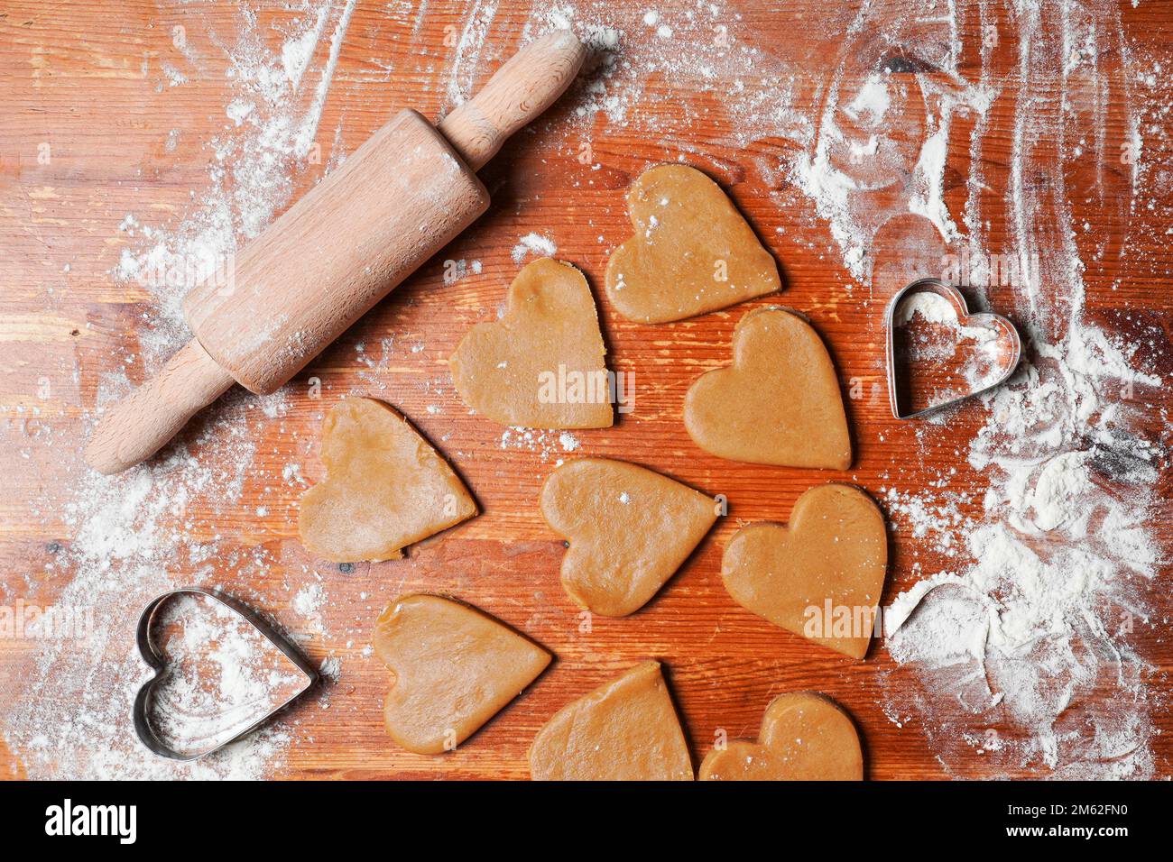 Heart cookies out dough, rolling pin and molds on table with flour. Valentines Day celebration. Home baking. Stock Photo
