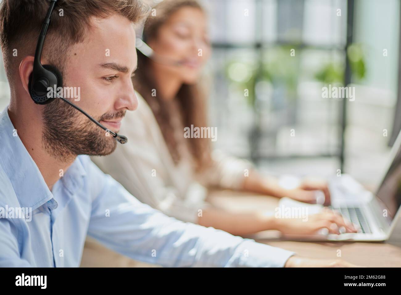 Customer Service Representative With Colleague Working In Office Stock Photo