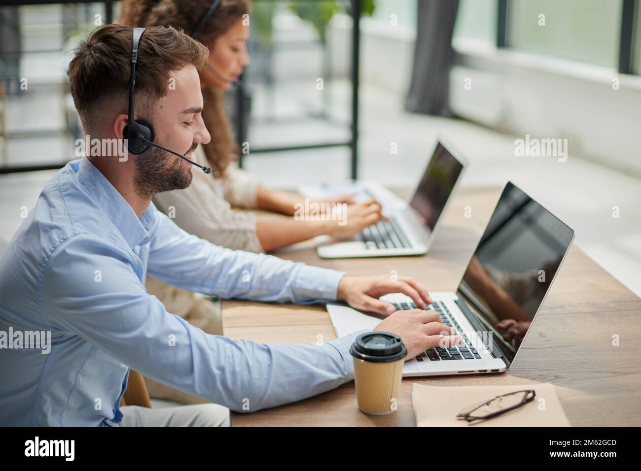 Customer Service Representative With Colleague Working In Office Stock Photo