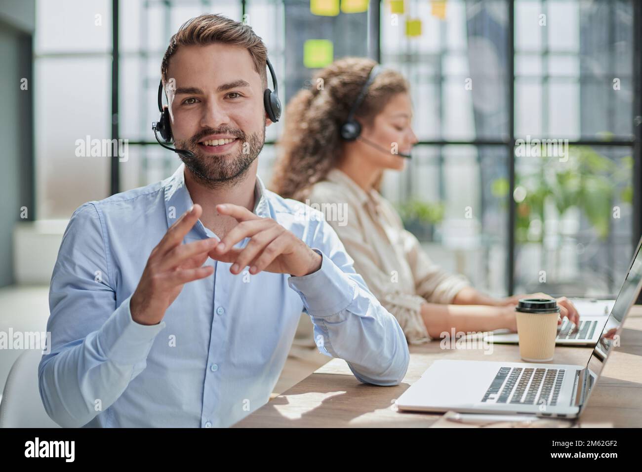 Customer Service Representative With Colleague Working In Office Stock Photo