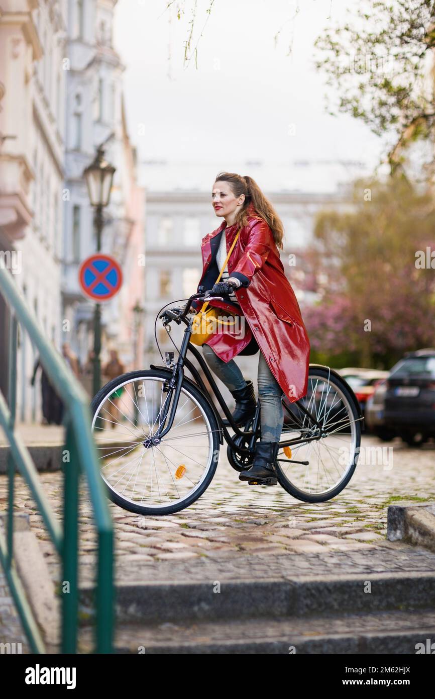 modern woman in red rain coat outdoors on the city street riding ...