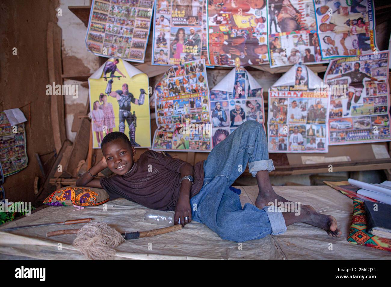 African teenage boy posing in front of his poster collection in his room . Enjoy sleeping under the stars. Stock Photo